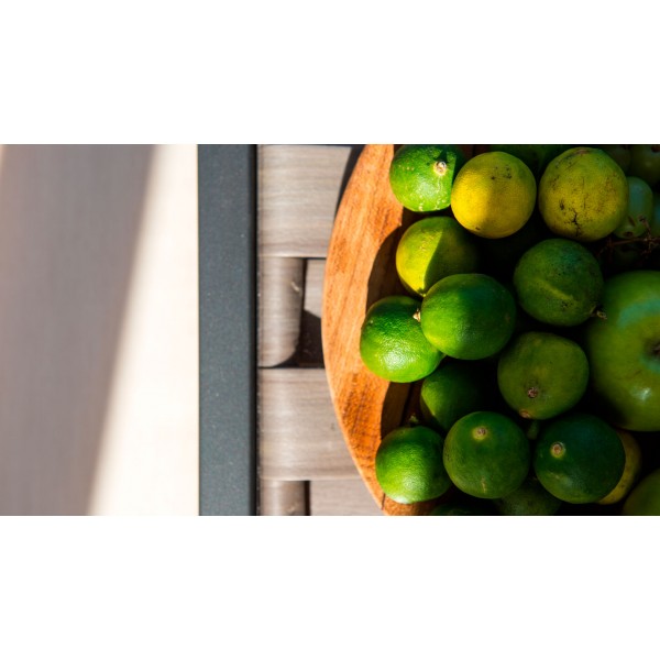 un bol de citrons verts sur une table en bois