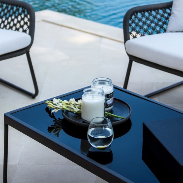 a black coffee table and chairs near a pool