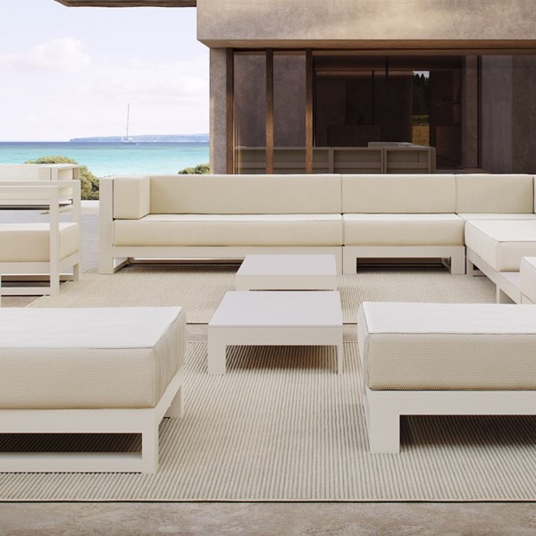 outdoor terrace furnished in beige and white tones, with two sofas, two coffee tables, a side table