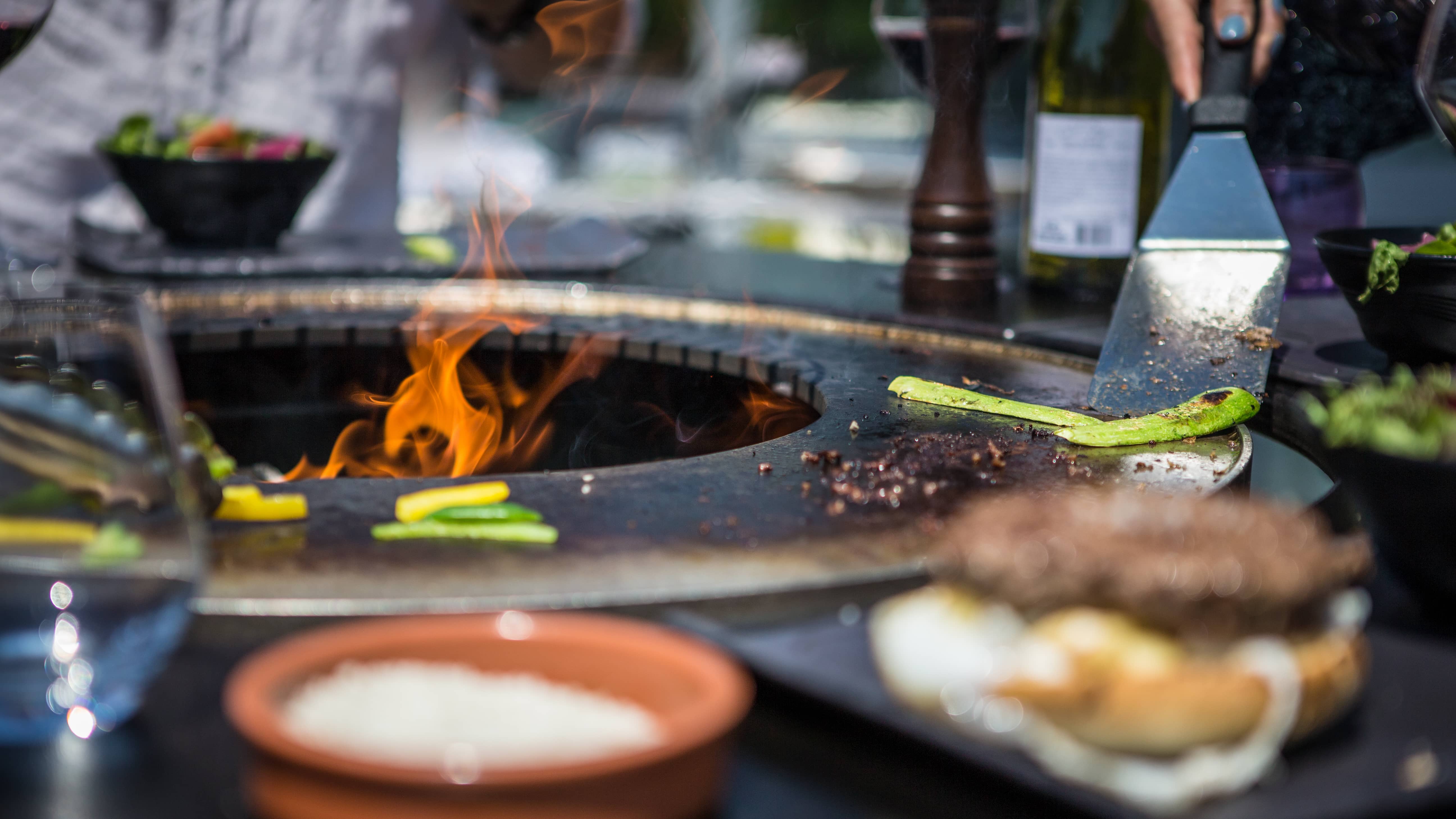 Making burgers on the outdoor high table VULX FUSION HIGH wood-burning barbecue